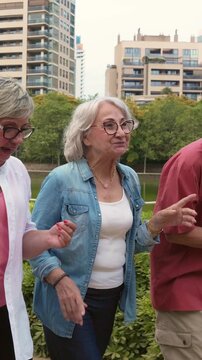 Three happy senior friends enjoying a pleasant walk and conversation outdoors in a city park