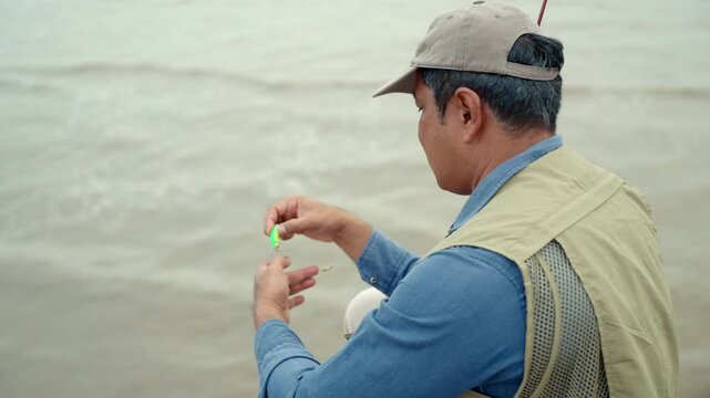 Close-up Senior man preparing fishing gear by the seaside. Retirement lifestyle active aging. Healthy longevity, outdoor recreation, peaceful leisure. Life insurance planning for a secure retirement.
