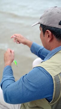 Close-up Senior man preparing fishing gear by the seaside. Retirement lifestyle active aging. Healthy longevity, outdoor recreation, peaceful leisure. Life insurance planning for a secure retirement.
