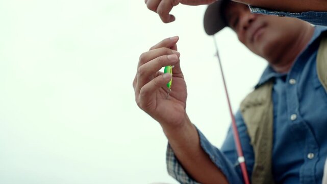 Close-up Senior man preparing fishing gear by the seaside. Retirement lifestyle active aging. Healthy longevity, outdoor recreation, peaceful leisure. Life insurance planning for a secure retirement.
