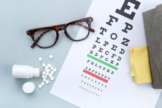 Eye test chart and glasses on blue background