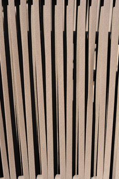 A detailed close up shot of tight beige woven fabric straps arranged vertically to form a textured pattern on outdoor furniture.