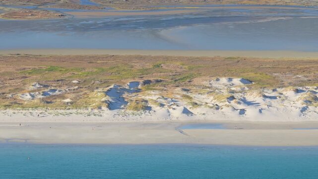 Aerial footage of Praia de Carnota, a wide sandy beach with dunes and turquoise water in Carnota, Galicia, Spain.