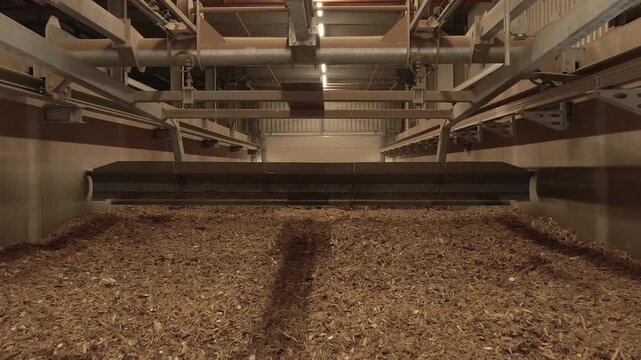 Overhead conveyors run above a large wood chip storage bay