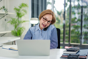 Fototapeta premium Adult Woman on Phone Working on Laptop at Desk Home Office Caree