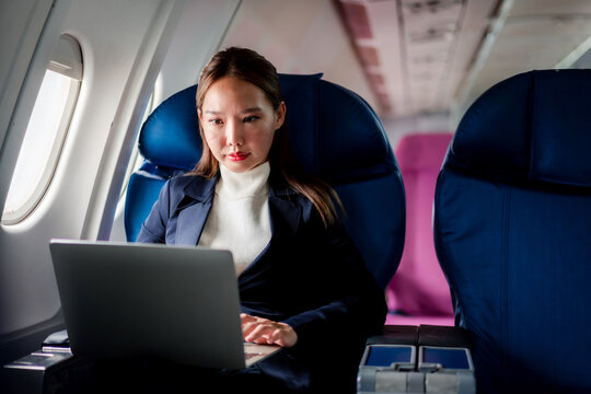 businesswoman focused working on a laptop inside a commercial airplane cabin during flight representing connectivity and remote productivity travel