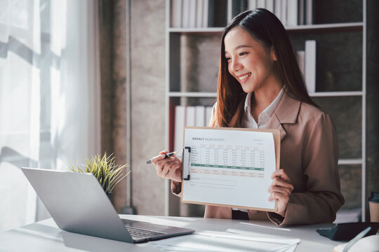 Asian Business Woman Analyzing Sales Data on Laptop in Office. F
