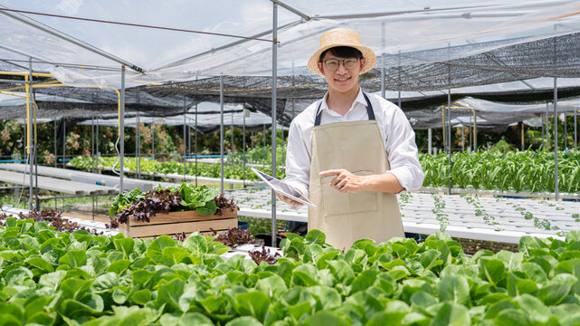 A man stands in a greenhouse pointing to a plant