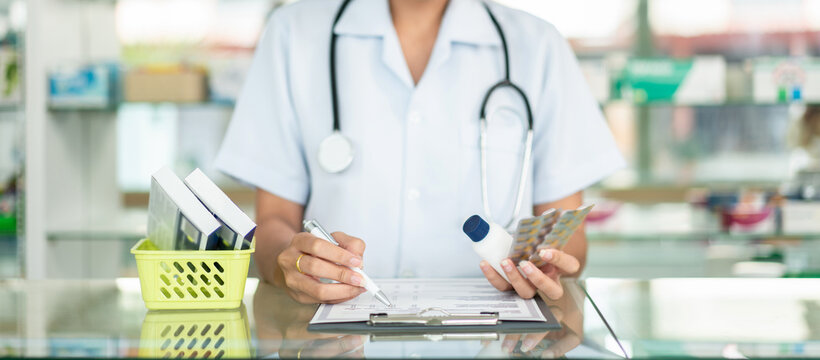 A nurse is writing on a clipboard in a pharmacy
