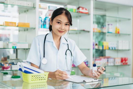 A woman in a white uniform is sitting at a desk in a pharmacy