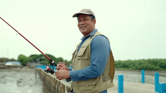 Portrait Senior man preparing fishing gear by the seaside. Retirement lifestyle active aging. Healthy longevity, outdoor recreation, peaceful leisure. Life insurance planning for a secure retirement.
