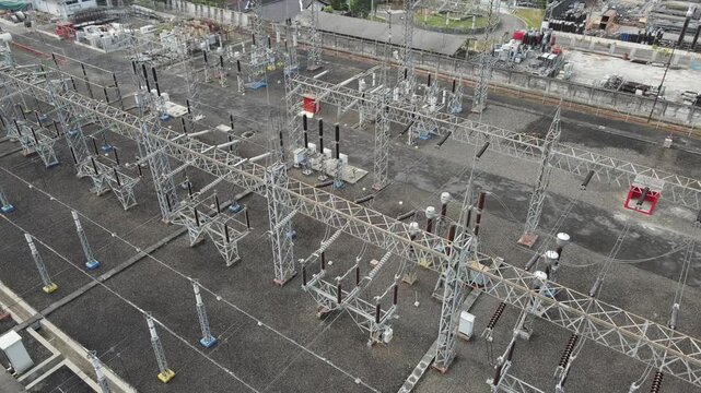 Aerial view of an electrical substation featuring complex metal structures, high-voltage power lines, and insulators in Purwokerto Selatan, Central Java, Indonesia.