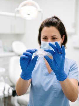 Dental professional closely examining clear aligners showcases patient-focused innovation in modern orthodontic healthcare services and health asset management.