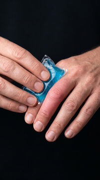 Retrato comercial de alta resoluci&oacute;n, primer plano extremo enfocado en las manos, mostrando a un adulto aplicando una peque&ntilde;a bolsa de hielo en gel a un dedo &iacute;ndice visiblemente hinchado
