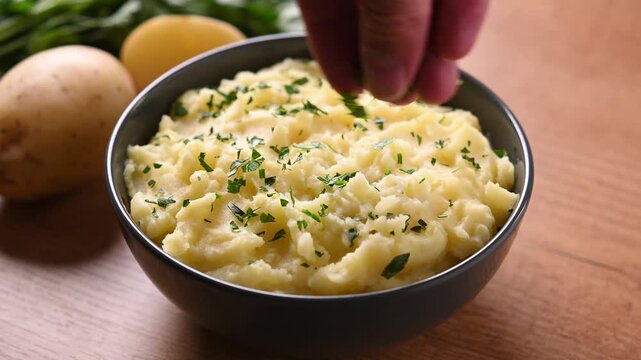Sprinkling fresh parsley over creamy mashed potatoes