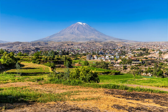 A view past the lush agricultural green fields and countryside on the outskirts of Arequipa with El Misti volcano backdrop in Peru in the morning