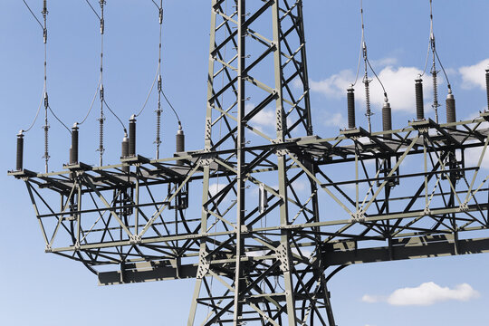 Electrical substation stands under blue sky. Steel framework holds insulators. Power lines connect grid equipment. Energy infrastructure supports industry. Electricity forms technical background.