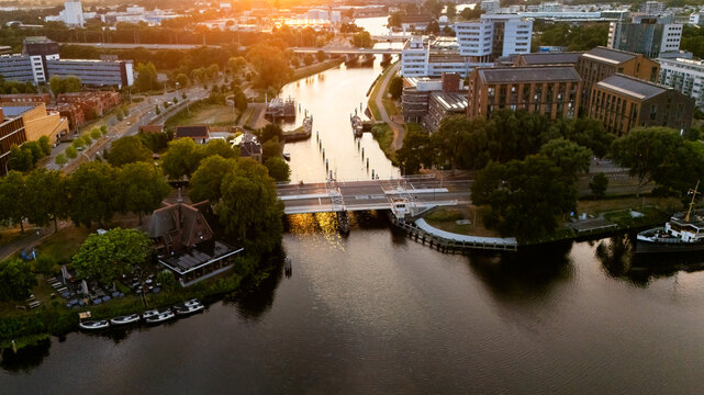 Aerial view of the canal and drawbridge in Zwolle during golden hour, surrounded by lush trees and modern architecture in Zwolle, Overijssel, Netherlands.