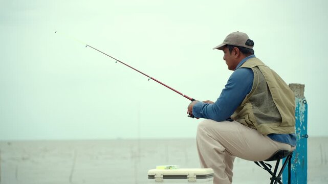 Happy senior man fishing by the sea during retirement. Active aging, outdoor leisure healthy longevity. Independence, retirement lifestyle, life insurance. Financial security for a fulfilling future.
