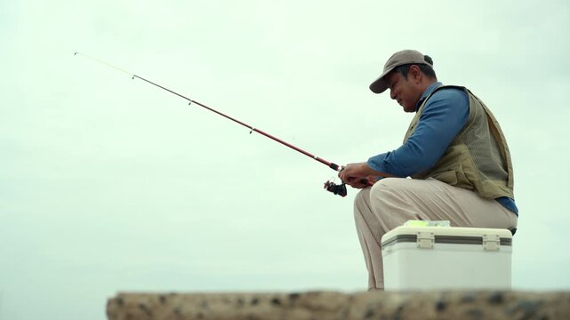 Happy senior man fishing by the sea during retirement. Active aging, outdoor leisure healthy longevity. Independence, retirement lifestyle, life insurance. Financial security for a fulfilling future.
