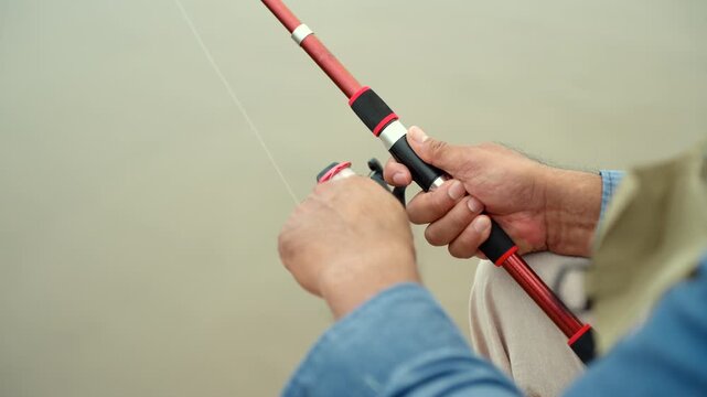 Close-up of a happy senior man holding a fishing rod by the sea. Enjoying life after retirement active aging. Healthy longevity, leisure lifestyle, life insurance and financial security concept.
