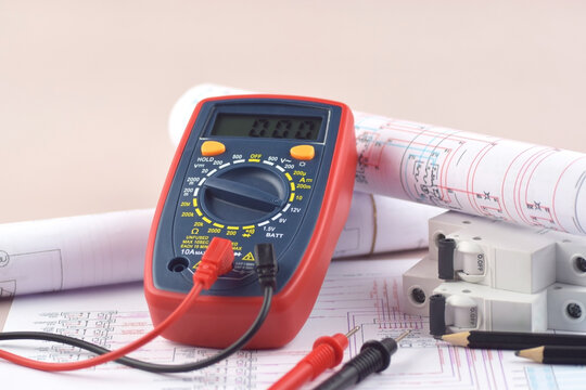 The digital multimeter electrical engineering drawings, circuit breaker and pencils.