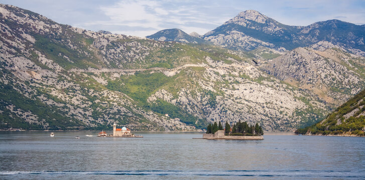 St. George Catholic Monastery on a small island in the Bay of Kotor near Perast, Montenegro, framed by rugged limestone mountains and calm water