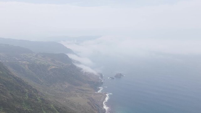Aerial footage captures the dramatic cliffs and rugged coastline around Garita da Herbeira near Meizoso, Spain. The coastline is jagged, with rocky outcrops and waves crashing against the shore.