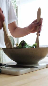 Woman preparing and mixing a fresh healthy salad in a bowl
