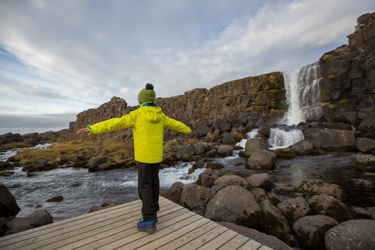 Cute child, boy, enjoying a sunny day in Oxararfoss Waterfall in Thingvellir National Park rift valley, Iceland autumntime