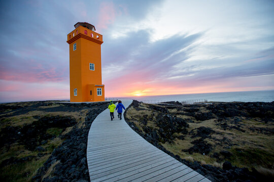 Children running on a path to lighthouse in lava field in beautiful nature in Snaefellsjokull National Park in Iceland, autumntime