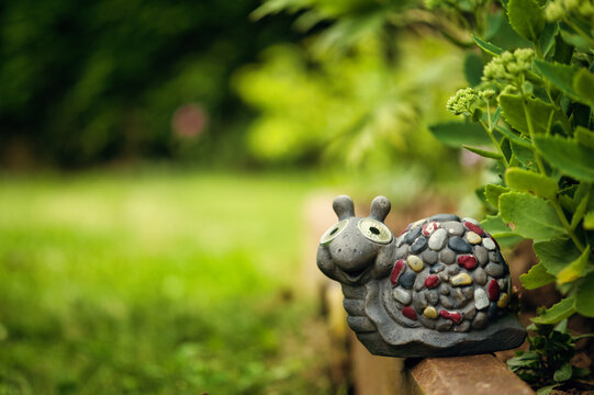 Gray snail garden ornament surrounded by greenery