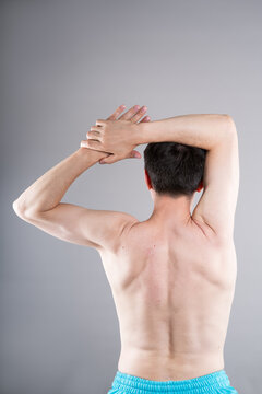Unrecognizable man shirtless performs exercises for muscles of upper back, arms and shoulder joint. Posture correction and physical therapy