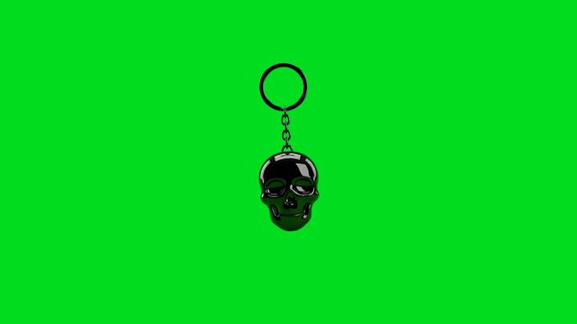 A shiny black skull keychain isolated against a vibrant green background