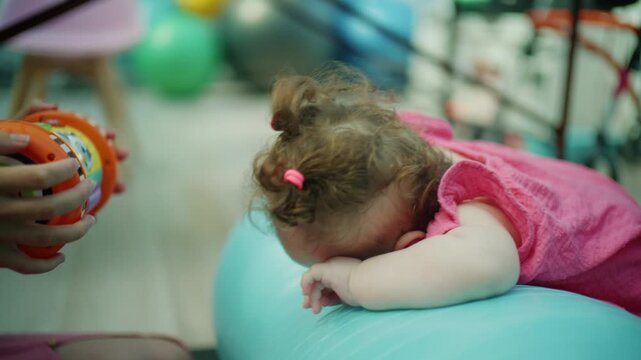 Baby girl receiving early intervention physical therapy. A child with a medical condition actively engaging in development exercises