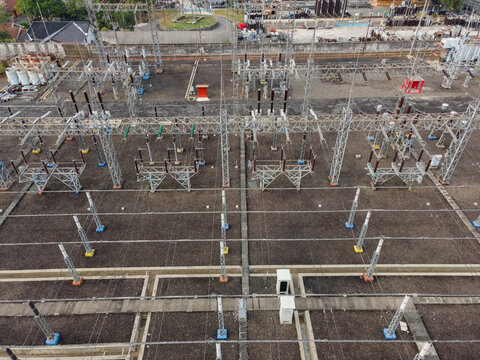 Aerial view of an electrical substation with metal structures, power lines, and transformers in an industrial area in Purwokerto Selatan, Central Java, Indonesia.