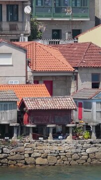 Vertical 9:16 video focusing on the iconic stone granaries (horreos) built on stilts along the waterfront in Combarro, Spain.
