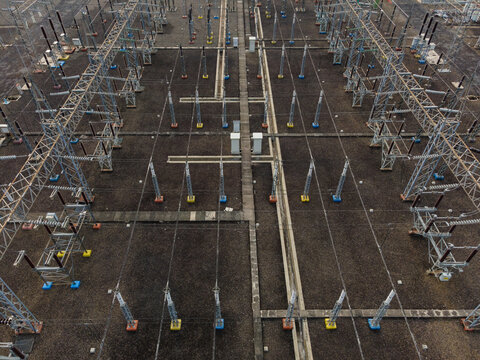 Aerial view of an electrical substation with metal power structures, high-voltage lines, and insulators in Purwokerto Selatan, Central Java, Indonesia.