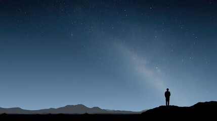Fototapeta premium A lone figure stands silhouetted on a ridge beneath a brilliant, star-filled sky. The Milky Way stretches across the cool blue night, illuminating distant mountains.