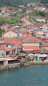 Vertical 9:16 aerial shot focusing on the waterfront houses of Combarro, Spain. This vertical format emphasizes the picturesque Galician architecture and scenic shoreline.
