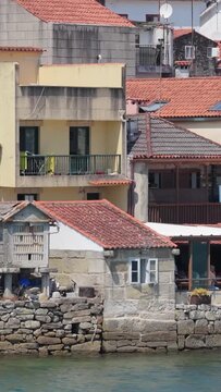 Vertical 9:16 video showing a close-up view of traditional stone waterfront houses with red-tiled roofs in Combarro, Spain.