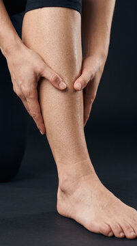 Retrato comercial de alta resoluci&oacute;n, encuadre ajustado en la parte inferior de la pierna, mostrando a un adulto masajeando el m&uacute;sculo tibial anterior dolorido a lo largo del hueso de la espinilla con
