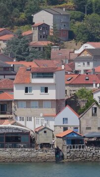 Vertical 9:16 video showing a close-up view of the traditional stone waterfront houses with red-tiled roofs in Combarro, Galicia, Spain.