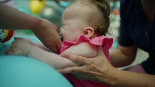 Baby learning new motor skills during pediatric physical therapy session. Therapist helping with exercises for improved development