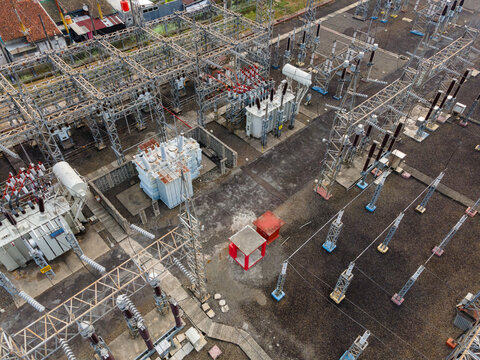 Aerial view of an electrical substation with high-voltage transformers, metal structures, and power lines in Purwokerto Selatan, Central Java, Indonesia.