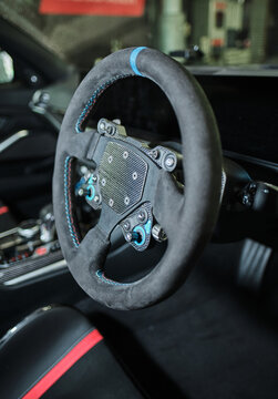 A Custom motorsport steering wheel with suede trim and exposed controls inside a modified performance car. Fast high speed car steering enhancements for the motor sports industry
