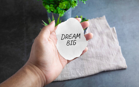 Hand Holding Torn Paper Displaying Dream Big Motivation Text