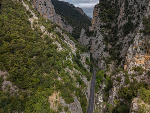 Aerial view of Gorges de la Pierre-Lys in the Pyrenees, featuring a winding road along the Aude river, steep rocky cliffs, and dense forests in Saint-Martin-Lys, Occitanie, France.