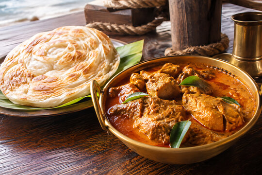 Authentic Malabar chicken curry with coconut and aromatic spices, served with Kerala parotta, traditional metal bowl,