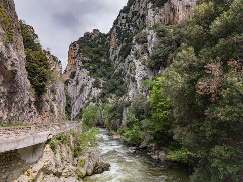 Aerial view of Gorges de la Pierre-Lys carved by the Aude river, featuring steep limestone cliffs, lush vegetation, and a winding road in Saint-Martin-Lys, Occitanie, France.